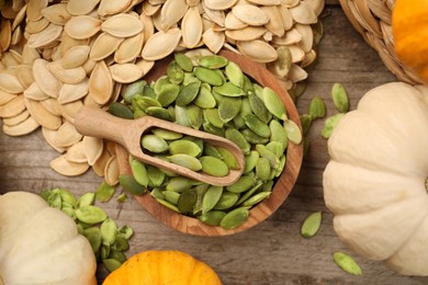 Many fresh pumpkins and seeds on wooden table, flat lay