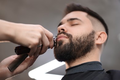 Photo of Professional hairdresser working with client in barbershop, low angle view