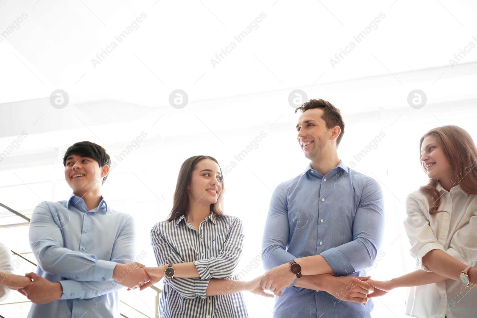 Photo of People holding hands indoors. Unity concept
