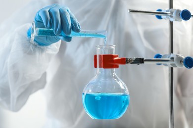 Photo of Scientist working with flask and test tube in laboratory, closeup