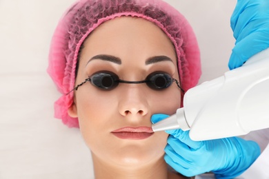 Photo of Woman undergoing laser tattoo removal procedure in salon, closeup