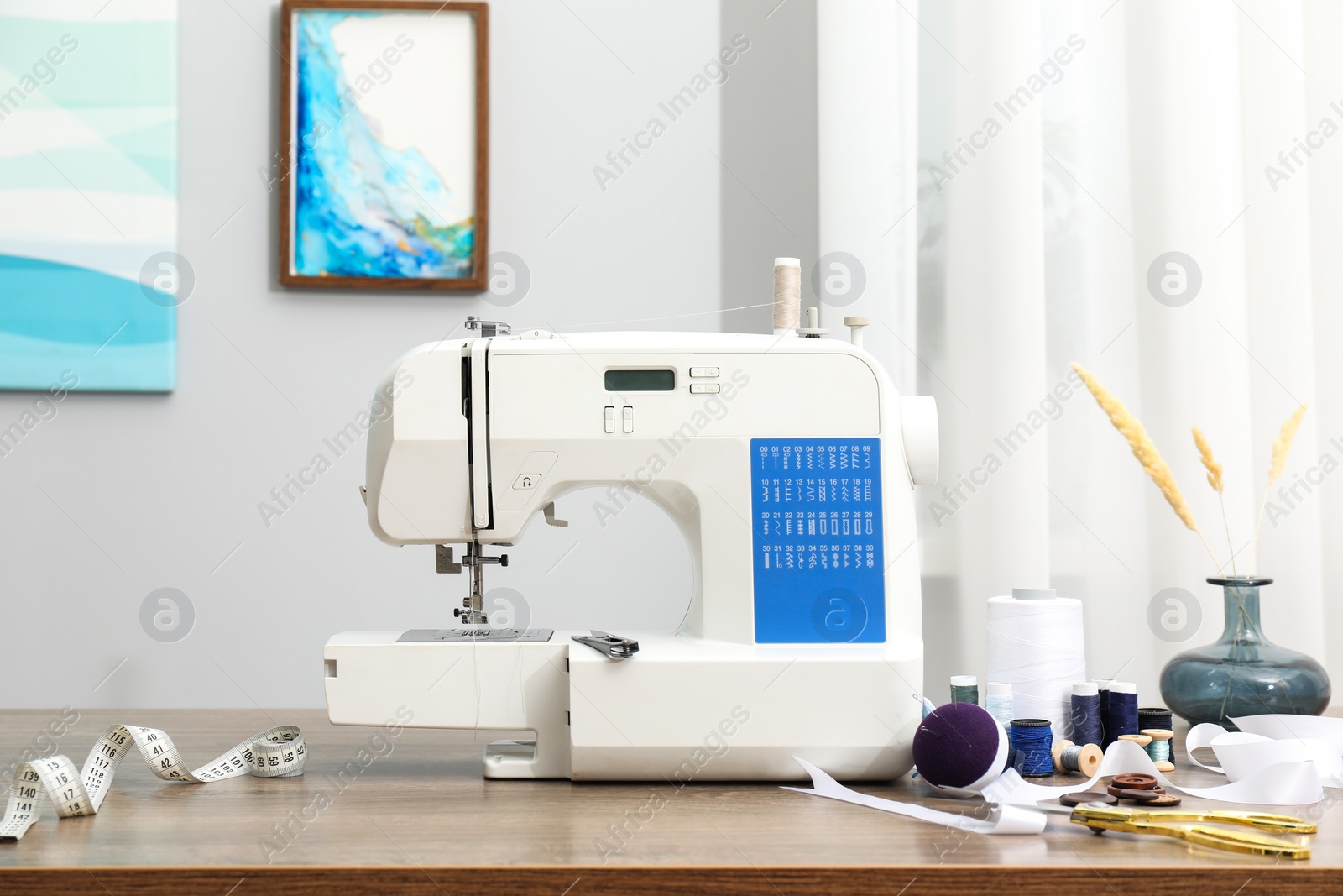 Photo of White sewing machine and craft accessories on wooden table indoors