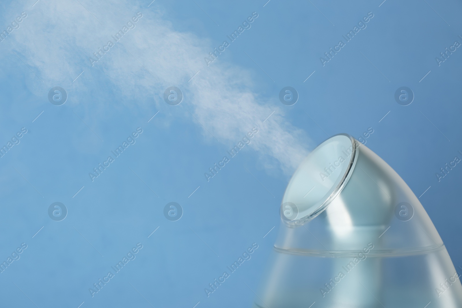 Photo of Modern air humidifier on light blue background, closeup. Space for text