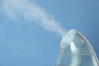 Modern air humidifier on light blue background, closeup. Space for text