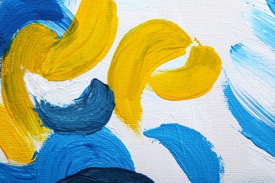 Photo of Beautiful strokes of blue and yellow oil paints on white canvas as background, closeup