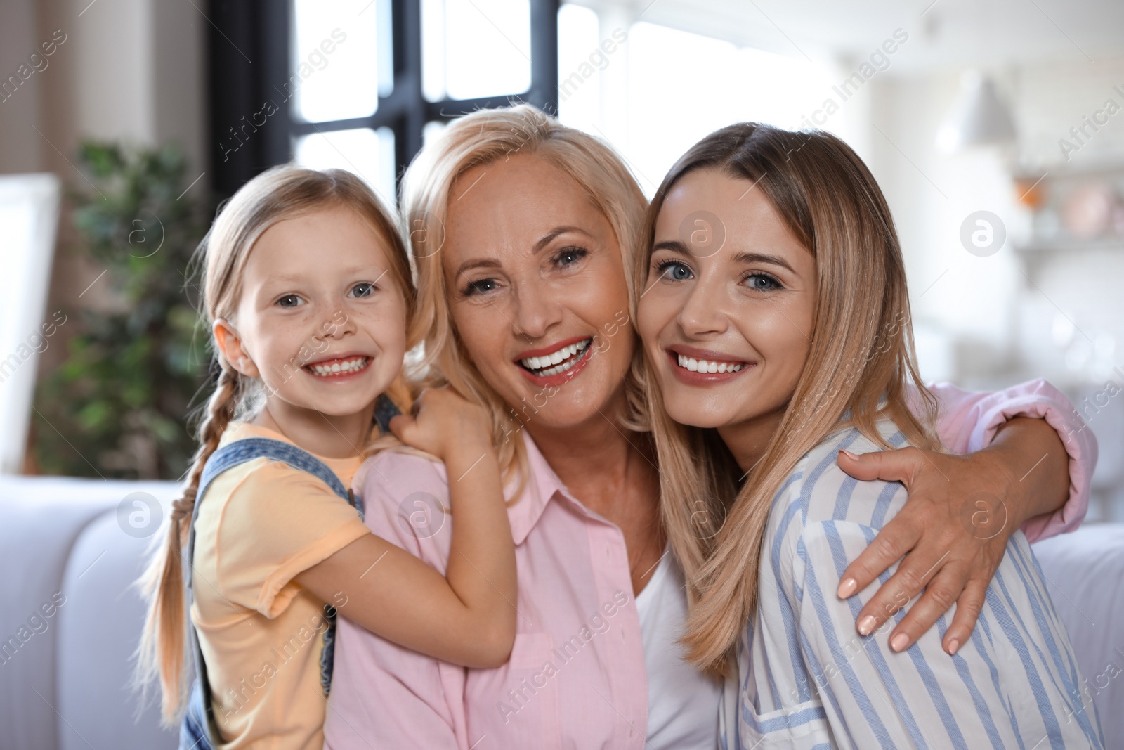 Photo of Young woman with mature mother and little daughter in living room