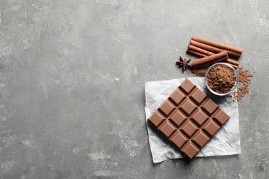 Chocolate bar and cocoa powder on grey background, flat lay. Space for text