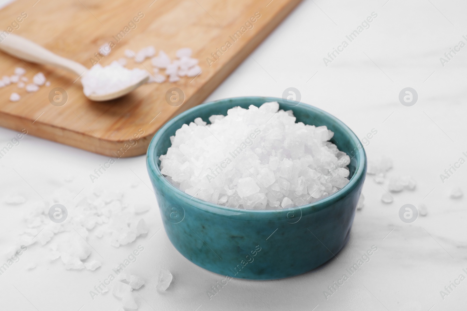 Photo of Bowl with sea salt on white marble table, closeup