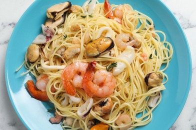 Photo of Delicious pasta with sea food on white marble table, top view