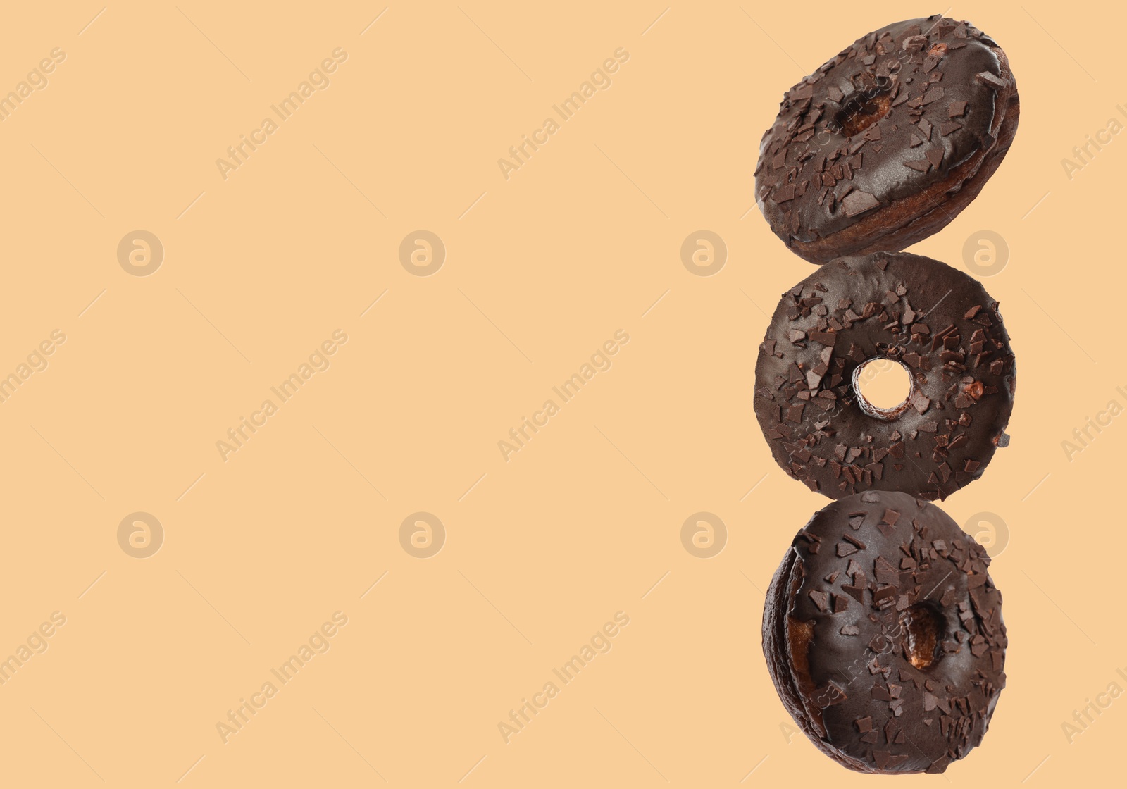 Image of Tasty chocolate donuts on moccasin color background, space for text