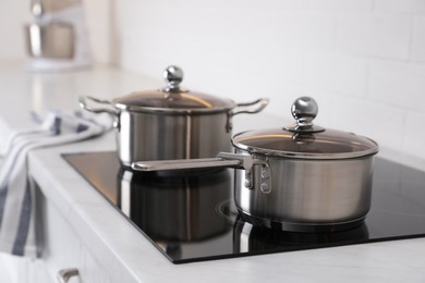 Photo of New clean pot and saucepan on cooktop in kitchen