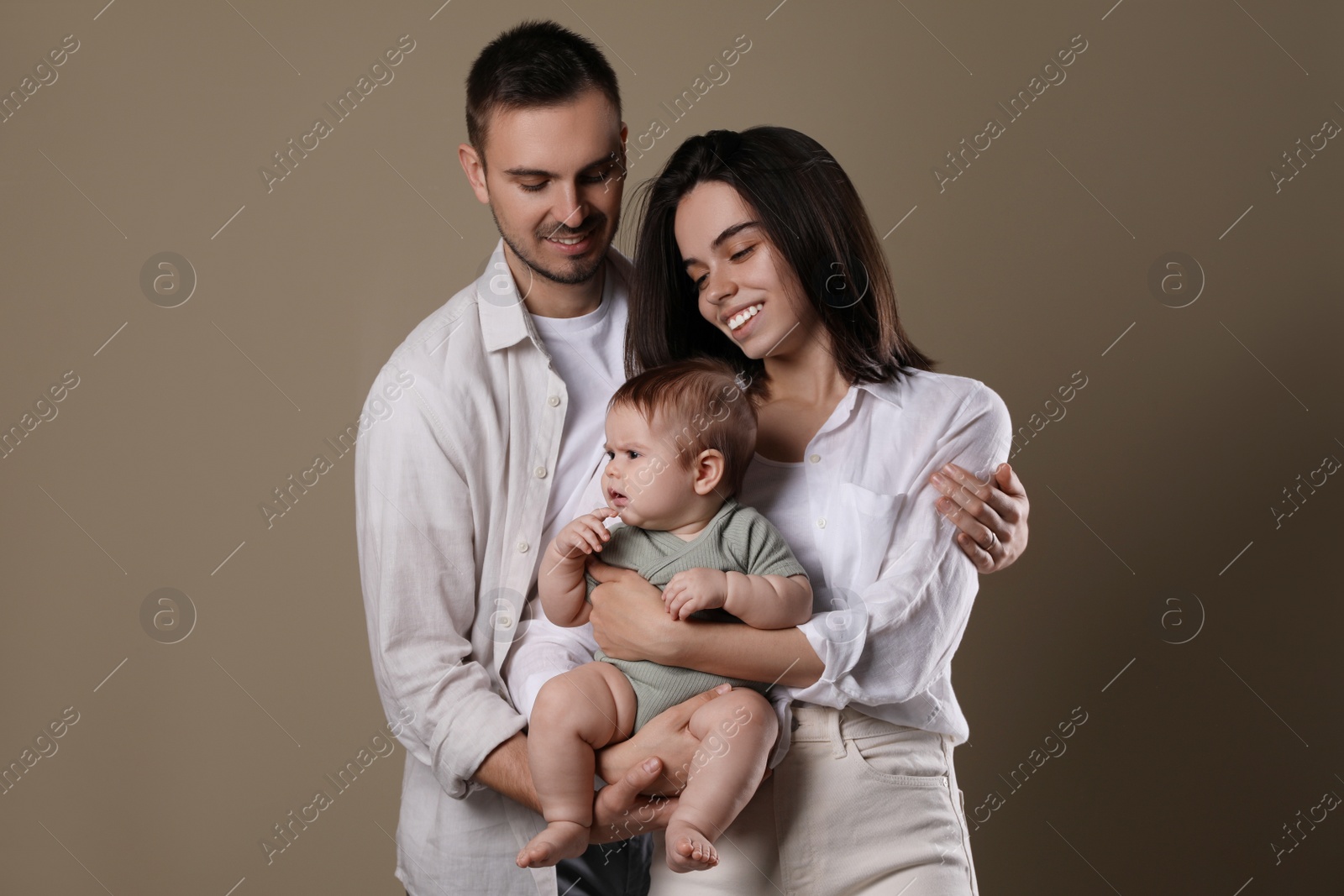 Photo of Happy family. Couple with their cute baby on beige background