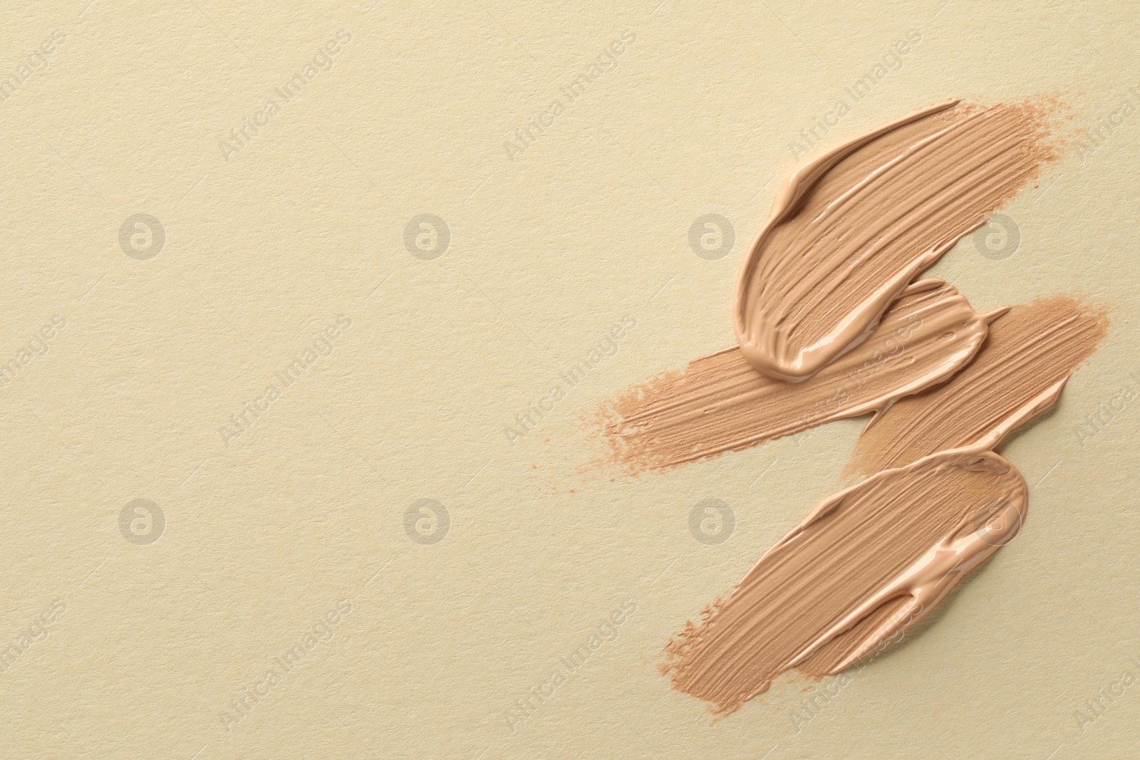 Photo of Sample of liquid skin foundation on beige background, top view. Space for text