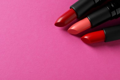 Photo of Beautiful lipsticks on pink background, above view. Space for text
