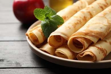 Delicious rolled  thin pancakes on wooden table, closeup