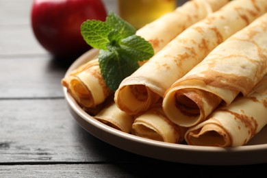 Photo of Delicious rolled  thin pancakes on wooden table, closeup