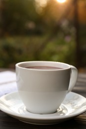 Photo of White cup with coffee on wooden table. closeup. Morning ritual