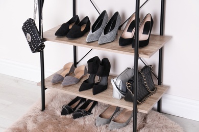 Photo of Shelving unit with stylish shoes and purses near white wall. Element of dressing room interior