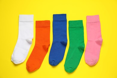 Photo of Different colorful socks on yellow background, flat lay