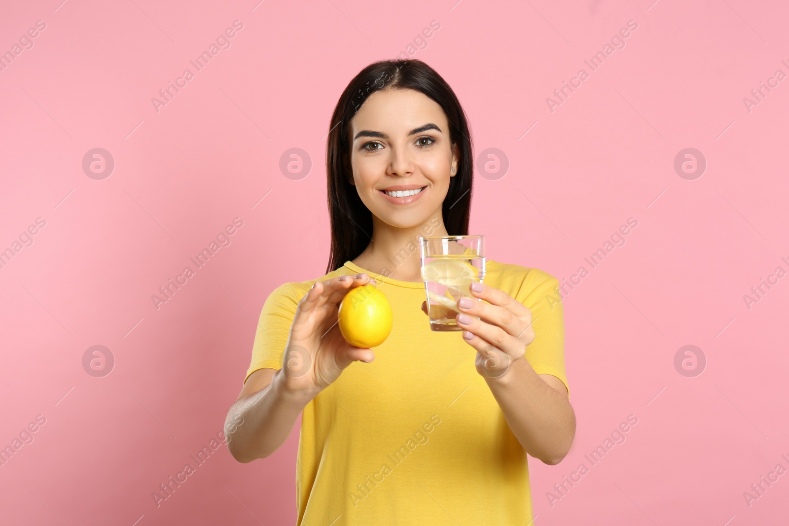 Photo of Beautiful young woman with tasty lemon water and fresh fruit on pink background