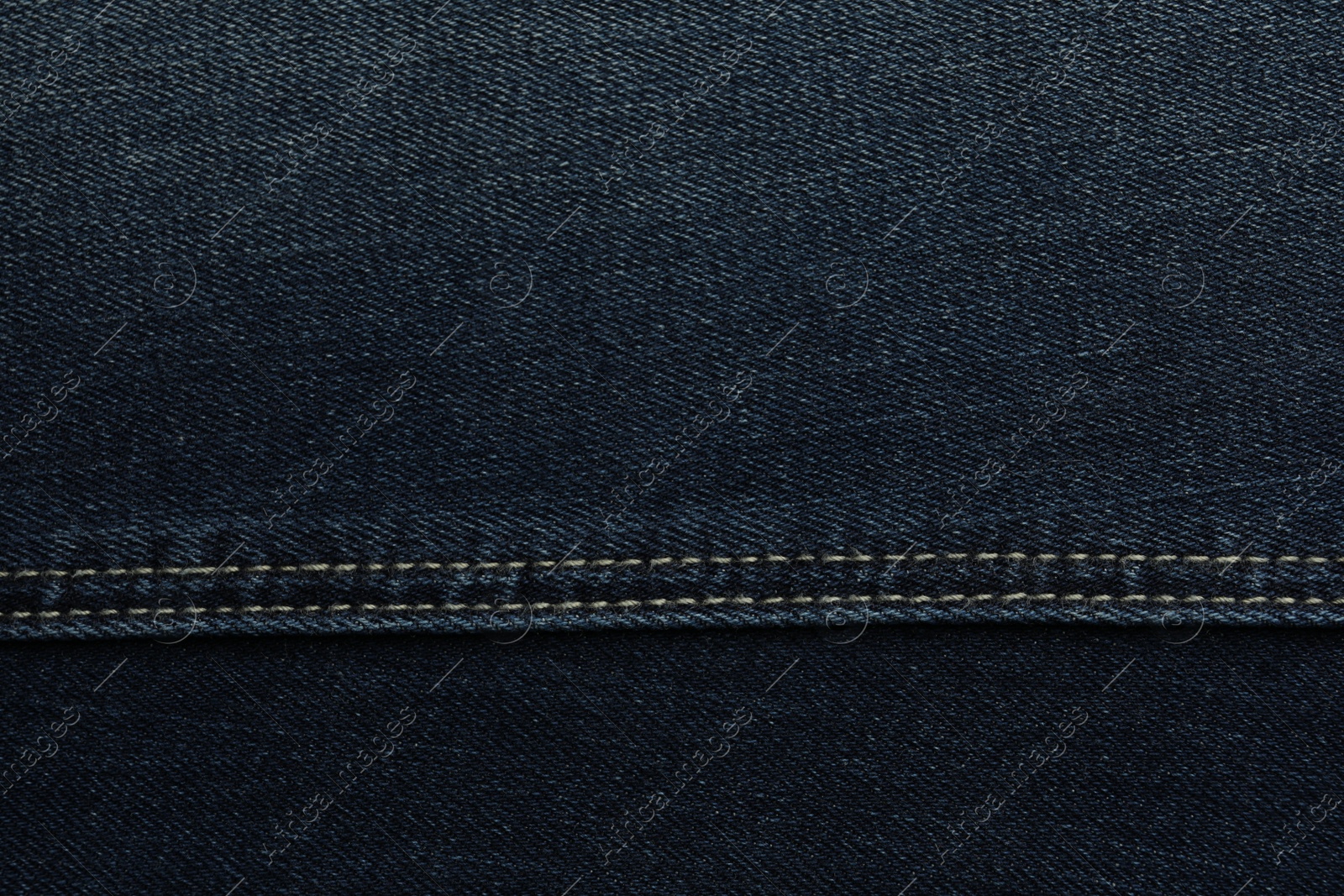 Photo of Texture of dark blue jeans as background, closeup