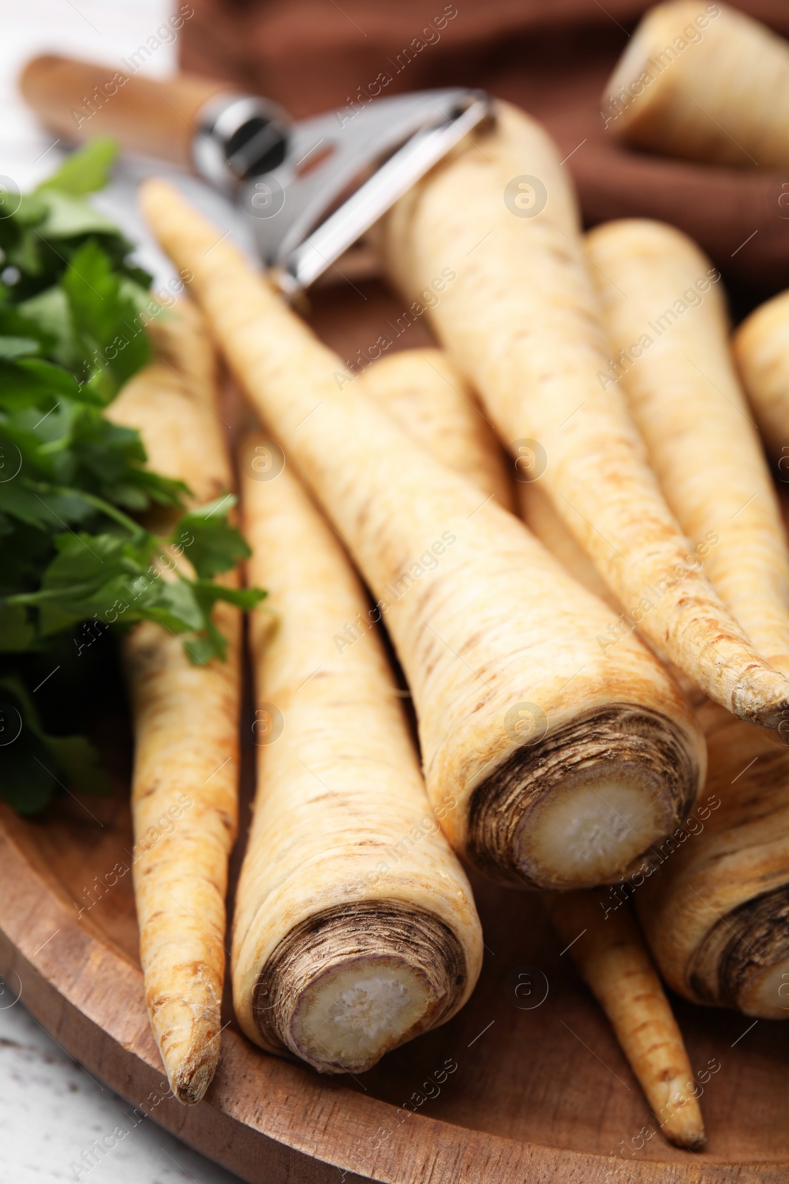 Photo of Raw parsley roots and fresh herb on wooden board, closeup