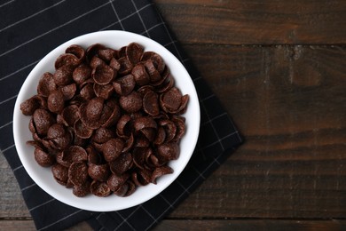 Photo of Breakfast cereal. Chocolate corn flakes in bowl on wooden table, top view. Space for text