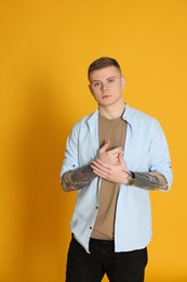 Photo of Young man with tattoos on yellow background