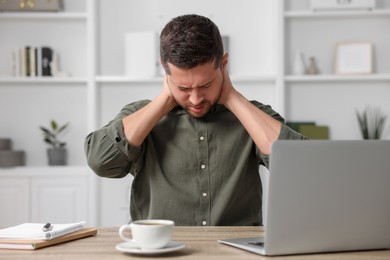 Man suffering from neck pain in office