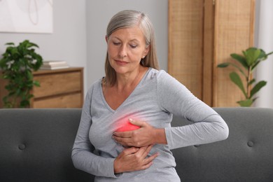 Image of Beautiful senior woman doing breast self-examination at home