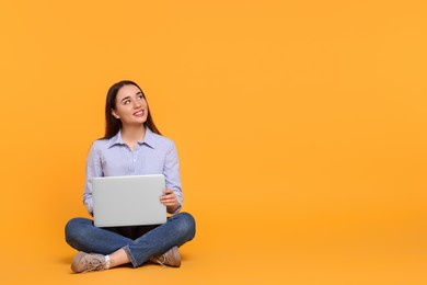 Photo of Smiling young woman with laptop on yellow background, space for text