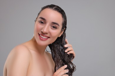 Photo of Beautiful happy woman washing hair on grey background. Space for text