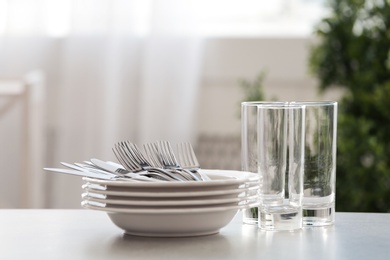 Set of clean dishes, cutlery and glasses on table indoors. Space for text