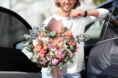 Photo of Man with beautiful flower bouquet near car on street, closeup