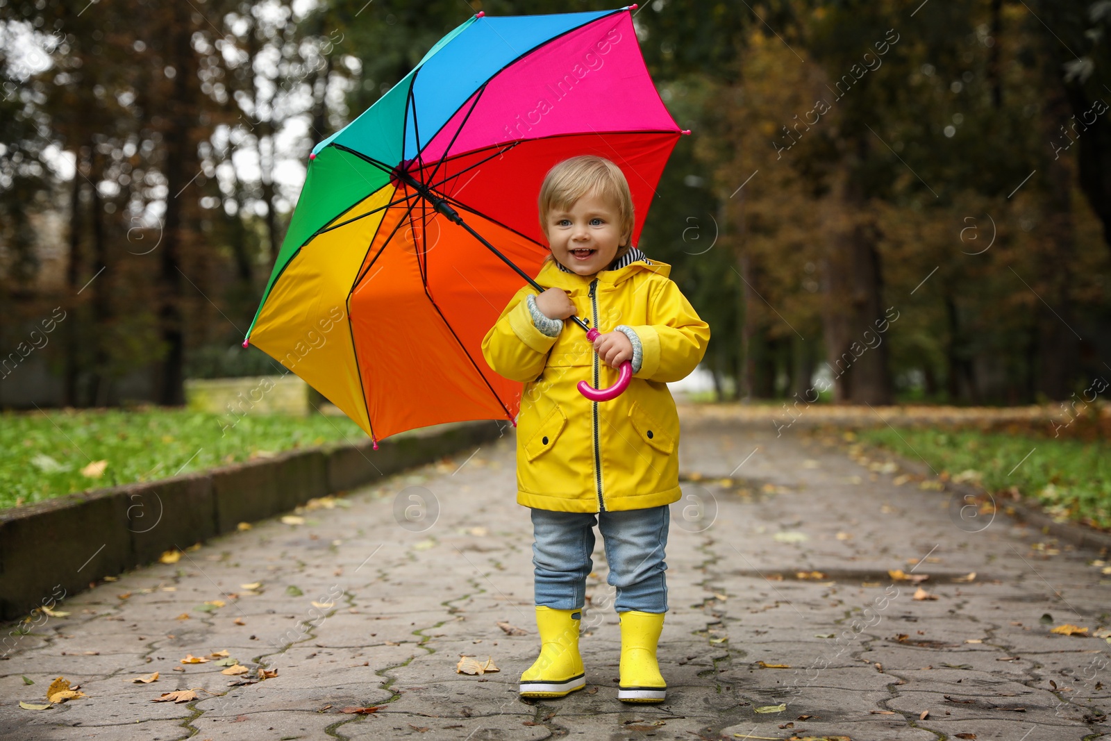 Photo of Little girl with colorful umbrella walking outdoors