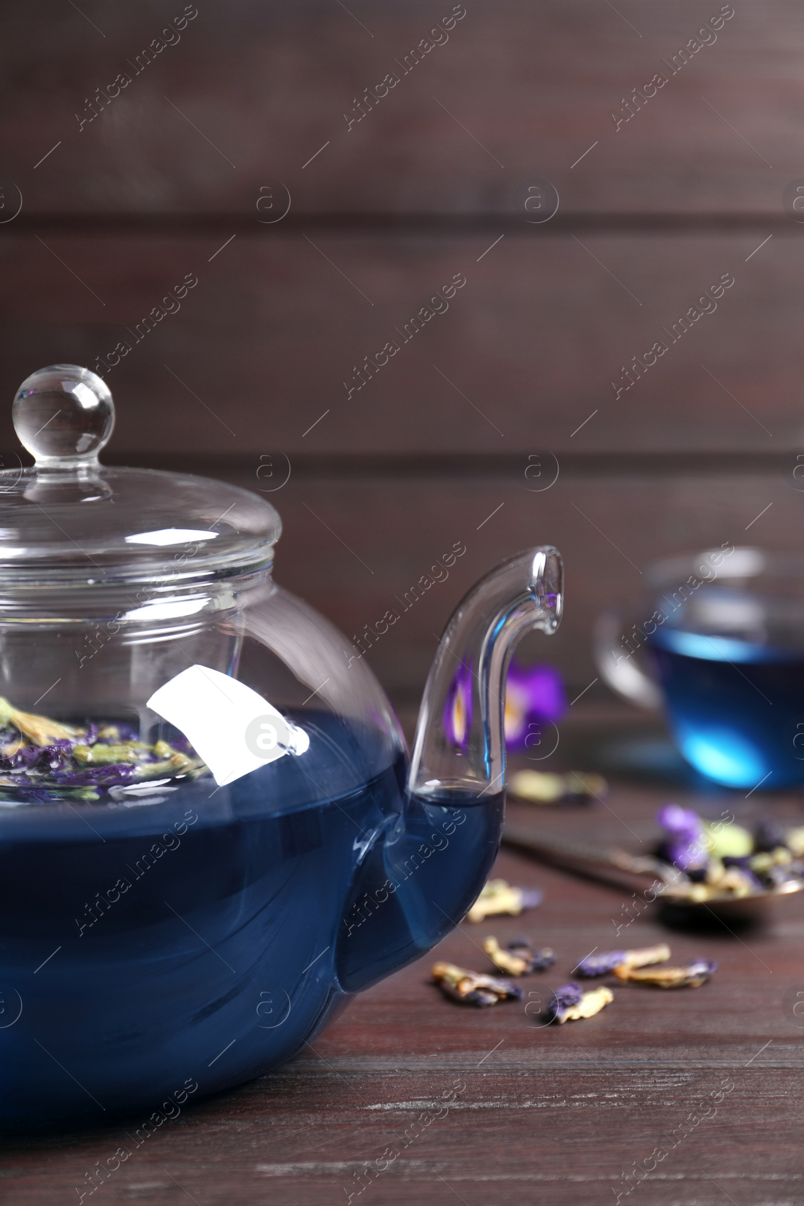 Photo of Organic blue Anchan in teapot on wooden table, space for text. Herbal tea