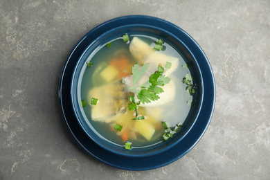 Photo of Delicious fish soup in bowl on grey table, top view