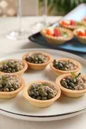 Delicious canapes with pate and capers on white table, closeup