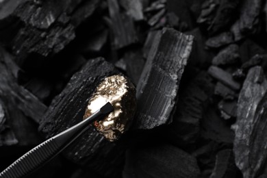 Photo of Tweezers with gold nugget above coals, closeup
