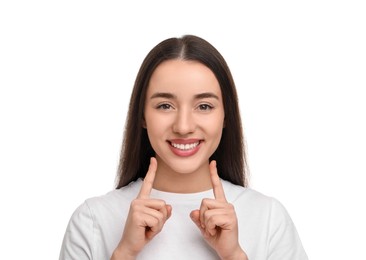 Photo of Young woman pointing at her clean teeth and smiling on white background