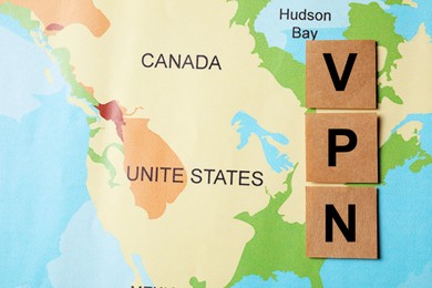 Paper notes with acronym VPN (Virtual Private Network) on world map, flat lay