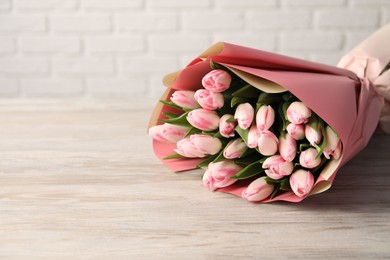 Beautiful bouquet of fresh pink tulips on light wooden table. Space for text