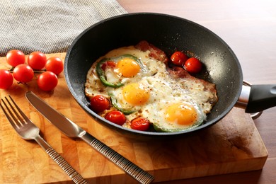 Photo of Delicious fried eggs with bacon, tomatoes and pepper served on wooden table