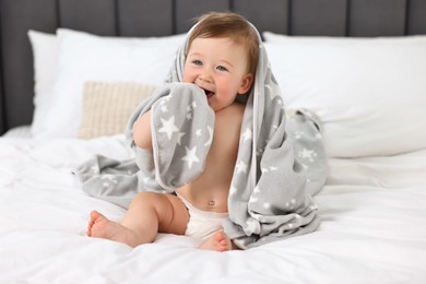 Photo of Happy baby boy with blanket sitting on bed at home