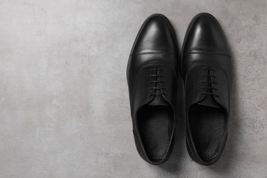 Photo of Pair of black leather men shoes on light grey surface, top view. Space for text