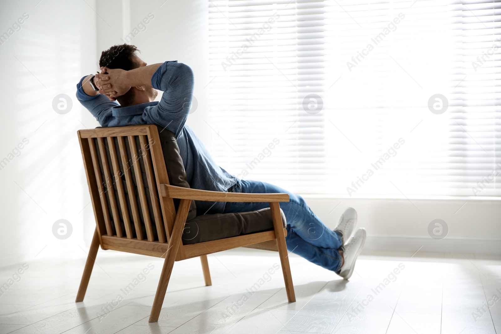 Photo of Young man relaxing in armchair near window at home