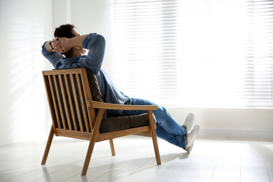 Young man relaxing in armchair near window at home