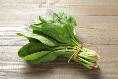 Photo of Bunch of fresh green healthy spinach on wooden table