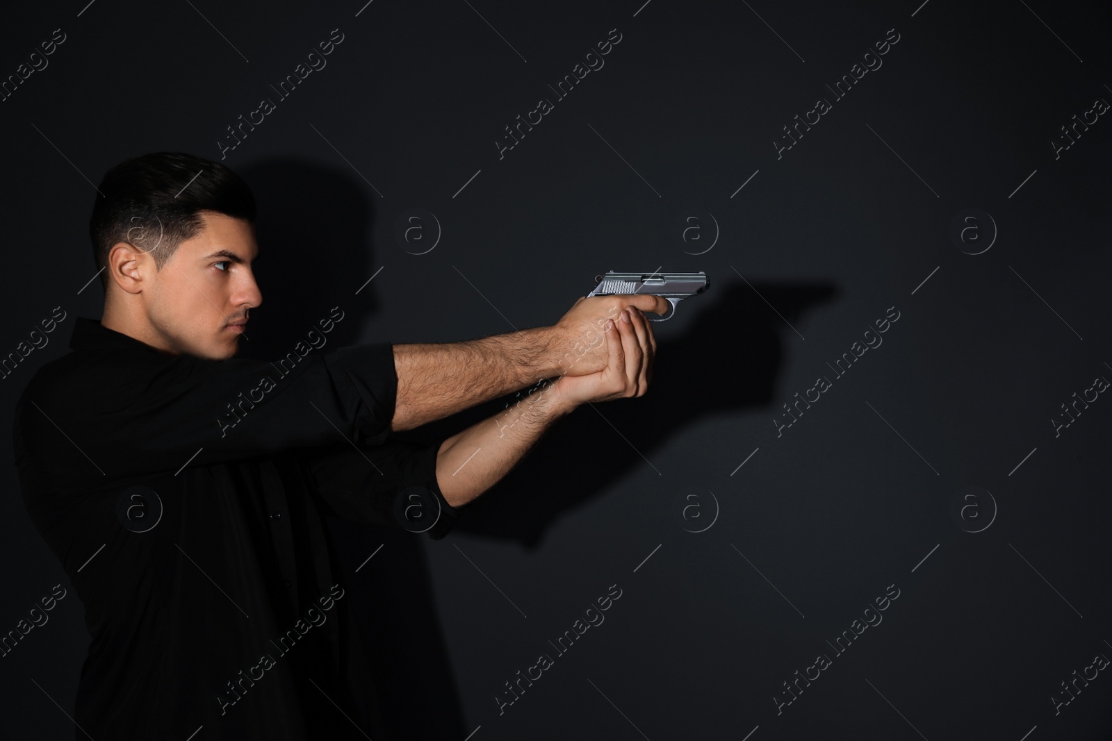 Photo of Professional killer with gun on black background