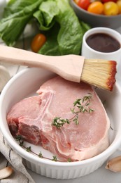 Raw meat, thyme and brush with marinade on light table, closeup